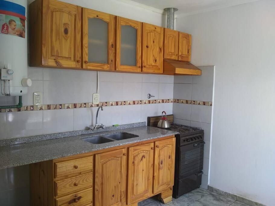 a kitchen with wooden cabinets and a sink and a stove at Alquiler diario in Malargüe