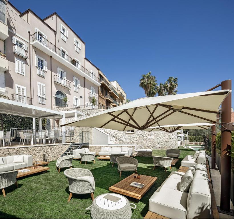 patio z białymi meblami i dużym parasolem w obiekcie Casa Clat w Cagliari