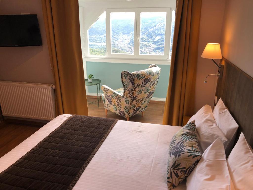 a bedroom with a bed and a chair and a window at Hôtel Panorama in Munster