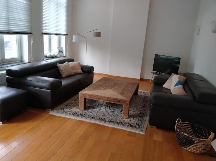 Sala de estar con sofá de cuero negro y mesa de centro en 'Nulle Part Ailleurs' en Dinant