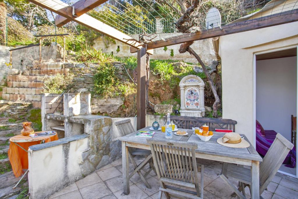 een patio met een tafel en stoelen onder een pergola bij Casa Pinzelli in Farinole