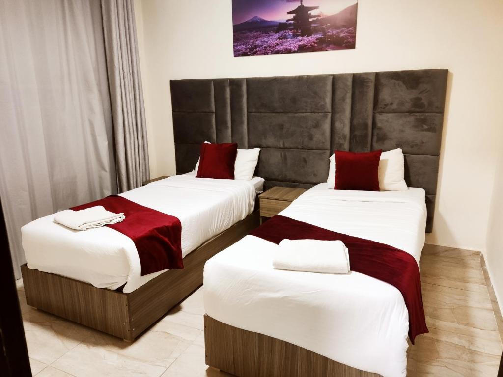 two beds in a hotel room with white and red sheets at Golden Plaza Hotel in Amman