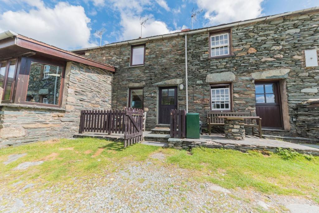 a stone house with a wooden gate and a bench at Fellside Cottage Coppermines Valley in Coniston