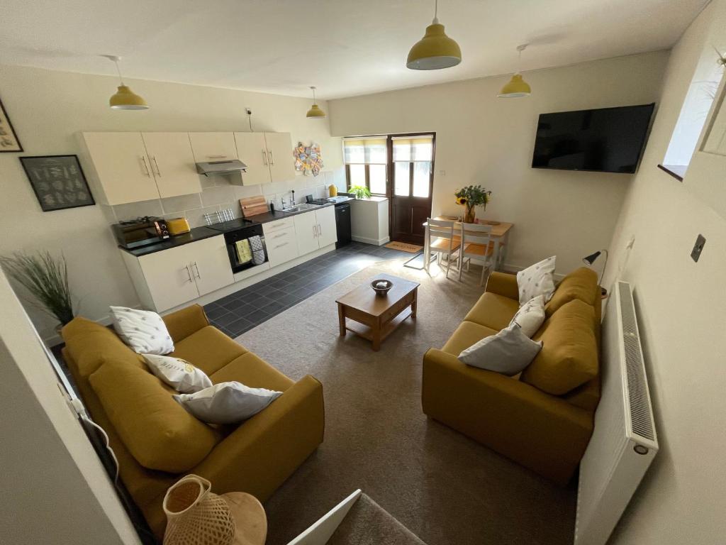 a living room with two couches and a kitchen at The Hive in South Molton