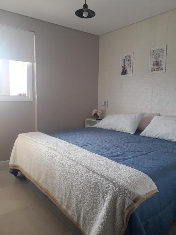 1 dormitorio con cama con sábanas azules y ventana en Departamento Torre Murguía en San Salvador de Jujuy