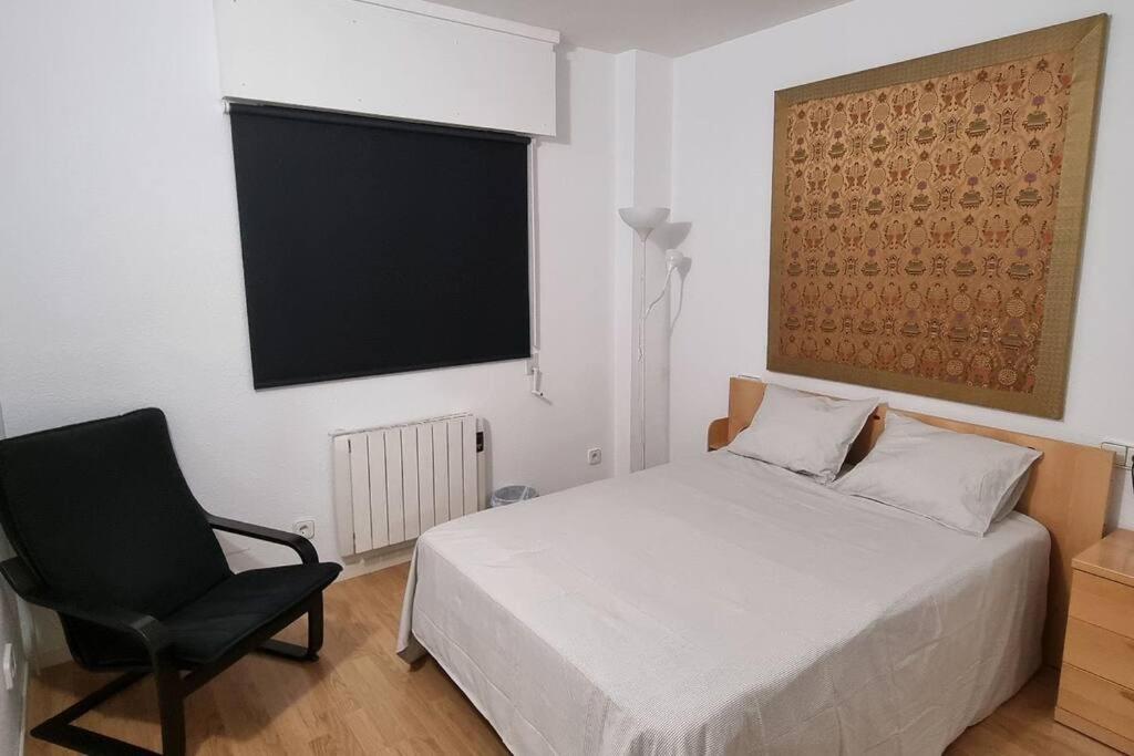 a bedroom with a bed and a chair and a television at Habitación Privada en el Centro de Madrid in Madrid