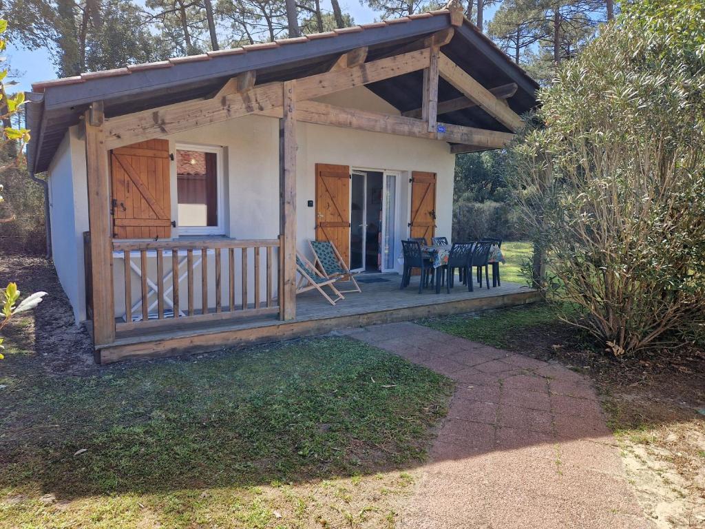 a small cottage with a porch and a table and chairs at Chalet T3 Nature Piscine Tennis in Ondres