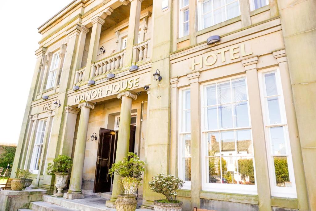 a hotel building with potted plants in front of it at Manor House Hotel, Cockermouth in Cockermouth