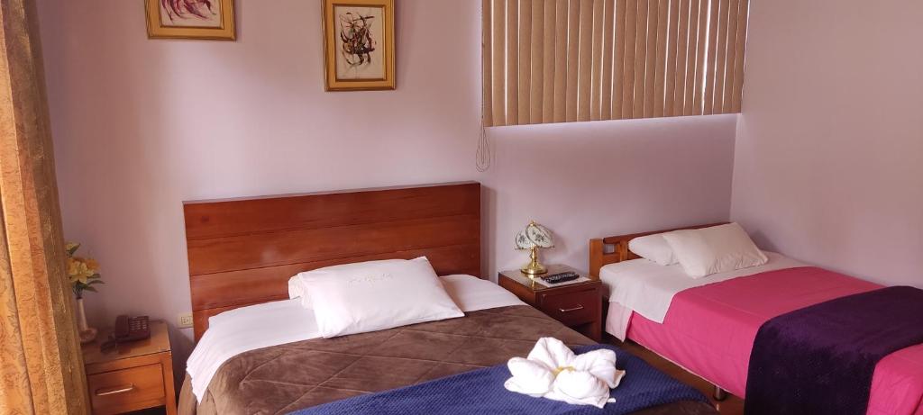 two beds in a small room with pink and purple at Hotel G&G in Cuenca