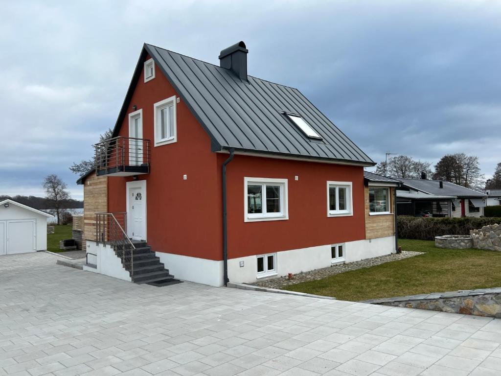 uma casa vermelha com um telhado preto na calçada em Valjeviken em Sölvesborg