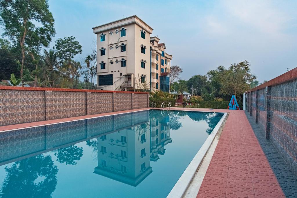 a swimming pool with a building in the background at Grand Selim Resort & Tour – GSRT in Sreemangal