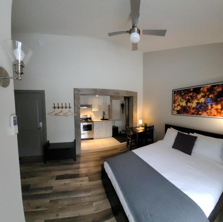 a bedroom with a large bed and a kitchen at Oberge Inn Val-David in Val-David