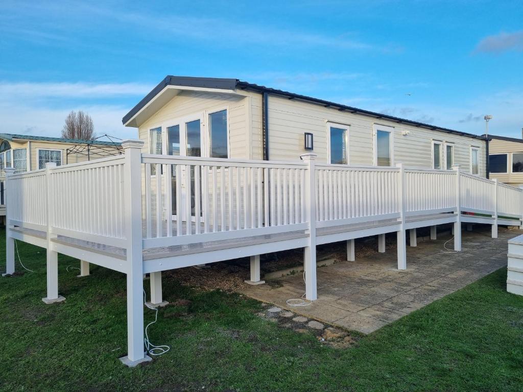 a mobile home with a white railing on a deck at Great 8 Berth Caravan With Decking At Valley Farm, Ref 46238pl in Great Clacton