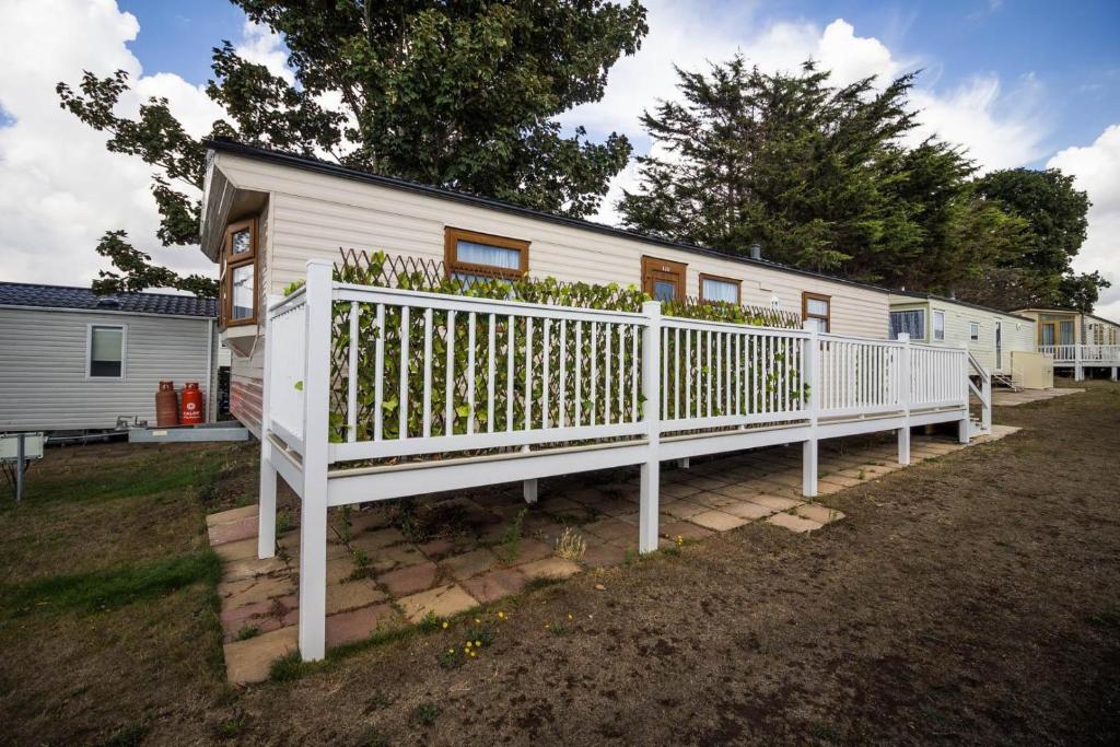 a white house with a white fence in front of it at 6 Berth Caravan With Decking Nearby Clacton-on-sea Ref 46128v in Great Clacton