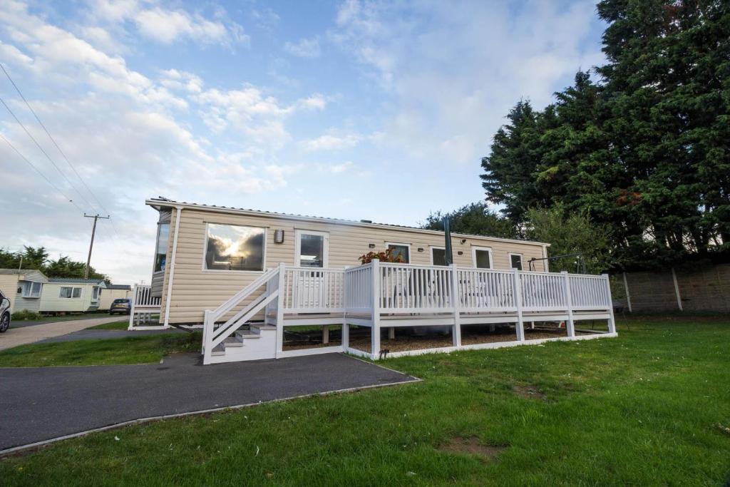 a tiny house with a porch and a deck at 8 Berth Caravan At Orchards Haven In Clacton-on-sea, Essex Ref 15007o in Clacton-on-Sea