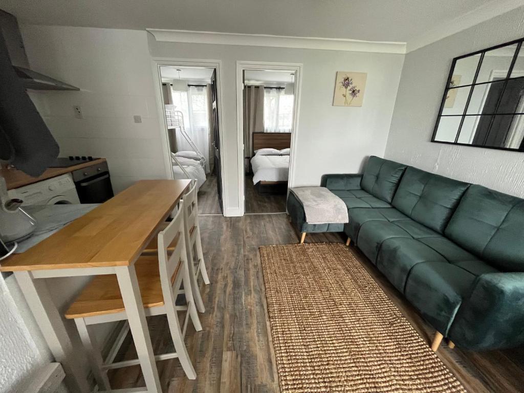 a living room with a green couch and a table at 88, Two bed Chalet on Belle Aire Holiday Park - sleeps 5, pet friendly, bed linen and towels included plus onsite entertainment available in Great Yarmouth