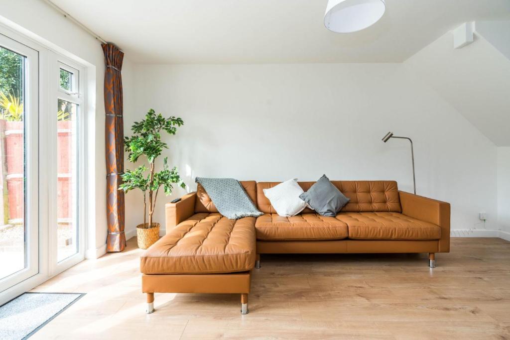 a brown leather couch in a living room with a window at Sleek and Stylish 2BD Home with a Garden Anerley in London