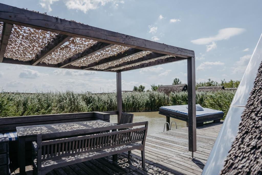 a wooden deck with a bench and a table at Seehütte Neusiedlersee inklusive Boot in Rust