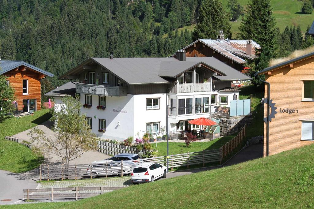 ein großes weißes Haus mit davor geparkt in der Unterkunft Landhaus Maria Theresia in Hirschegg