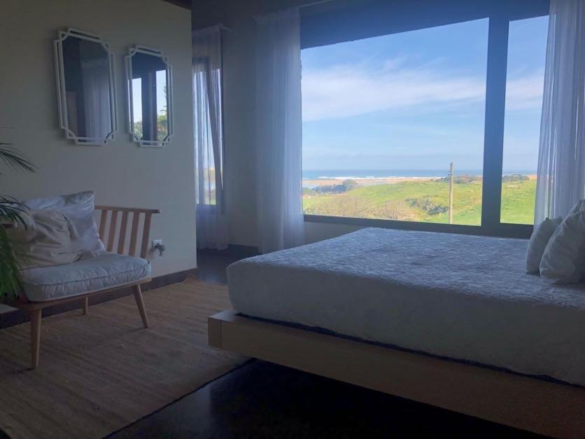 um quarto com uma cama e uma grande janela em La Carrera, Mogro Cantabria em Mogro