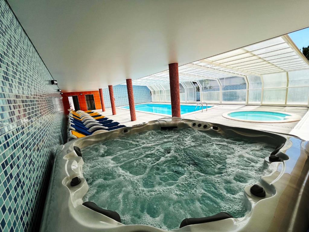 a swimming pool with a hot tub in a building at Hotel Colmeia in Monte Real