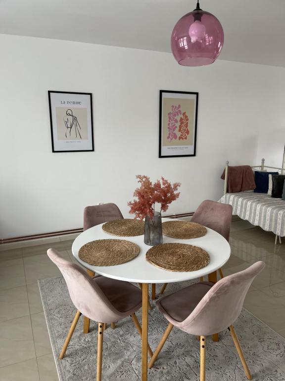 a dining room with a white table and pink chairs at Apartamenty Cud Miód in Krosno
