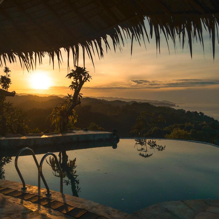 Ama Awa Resort في Kemadang: مسبح مع غروب الشمس في الخلفية