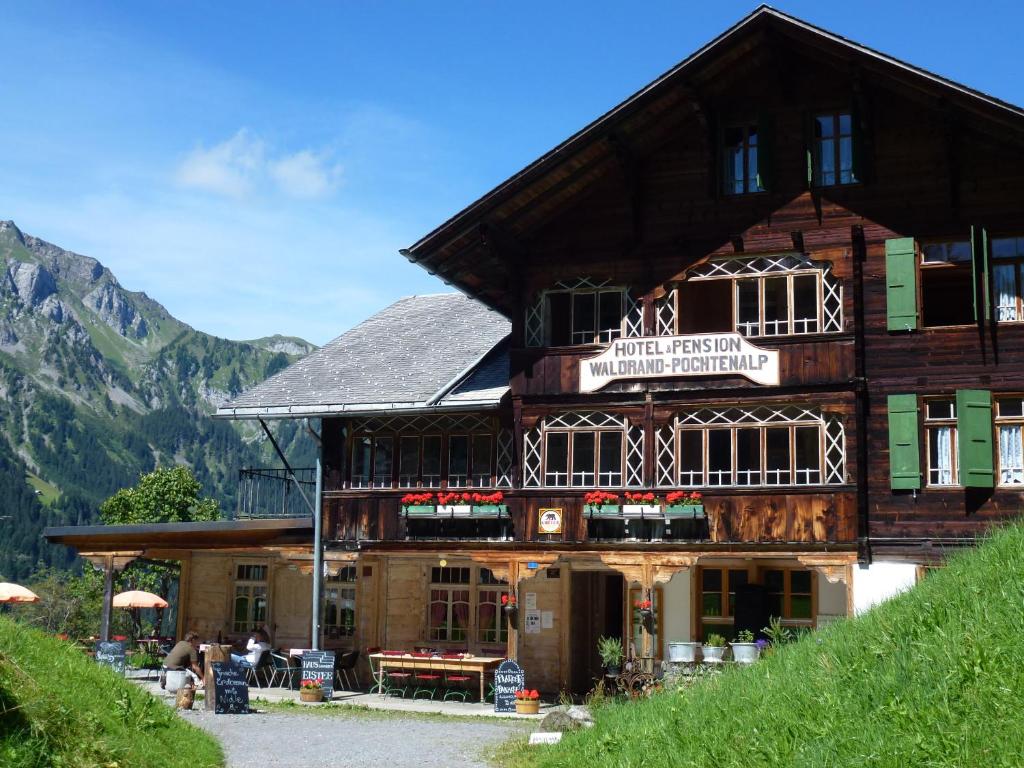a large wooden building with people sitting in front of it at Hotel Waldrand in Kiental