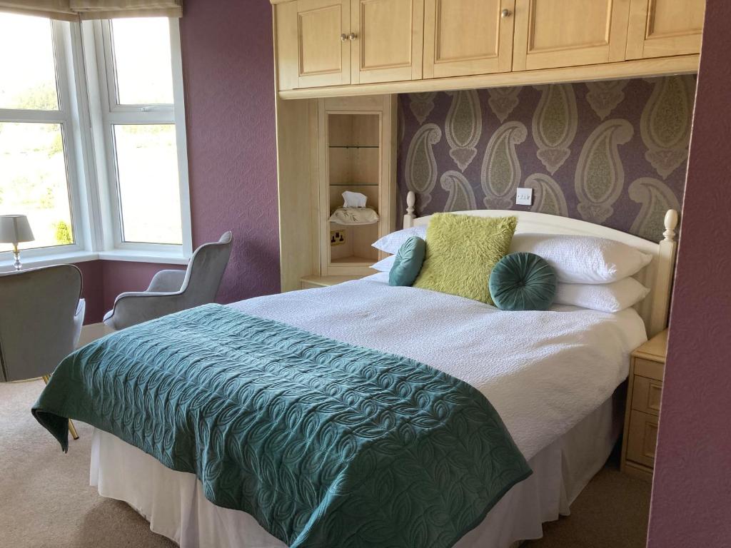 a bedroom with a large bed with a green comforter at Llety Betws in Betws-y-coed