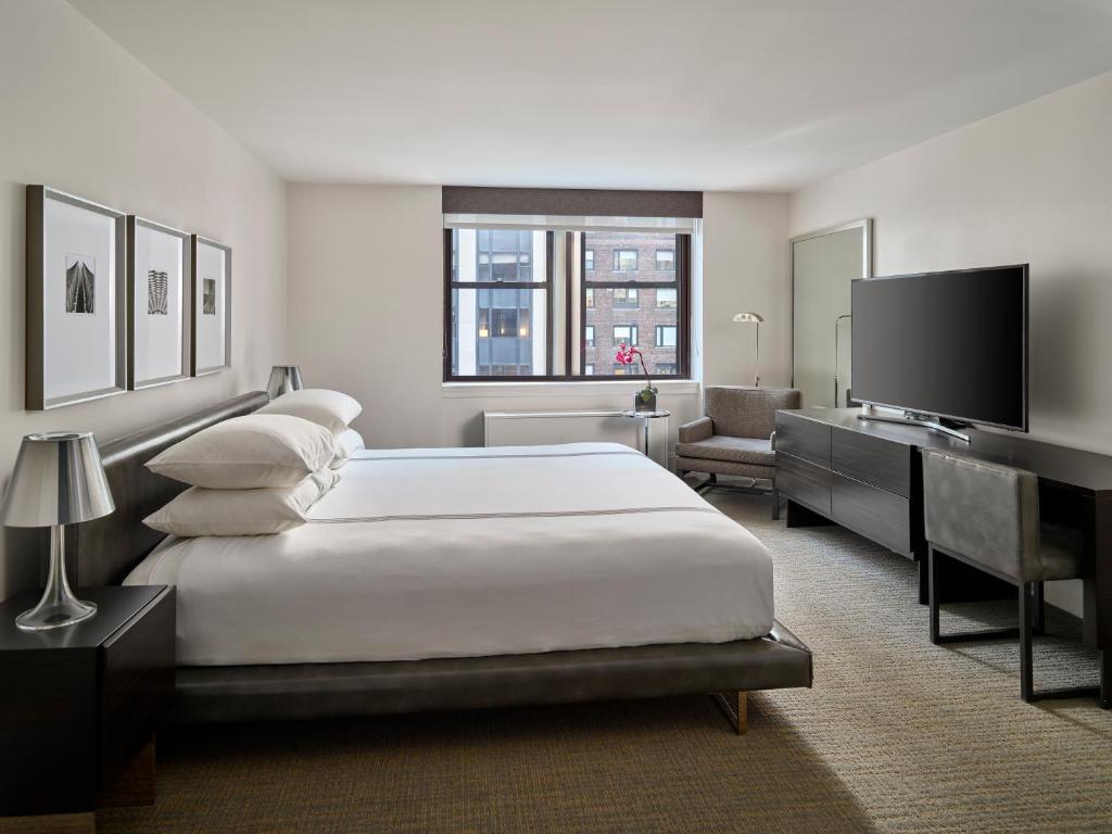 a bedroom with a large white bed and a television at AKA Central Park in New York