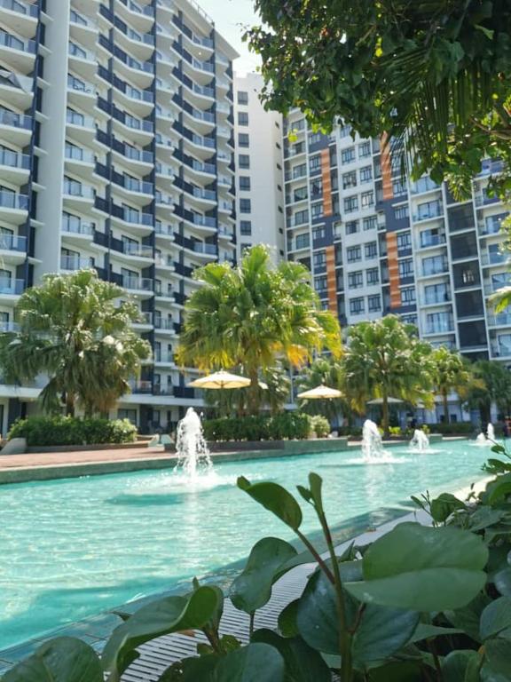 a swimming pool with fountains in front of tall buildings at D'Sunset Guesthouse TIMURBAY SEAFRONT -KUANTAN in Kuantan