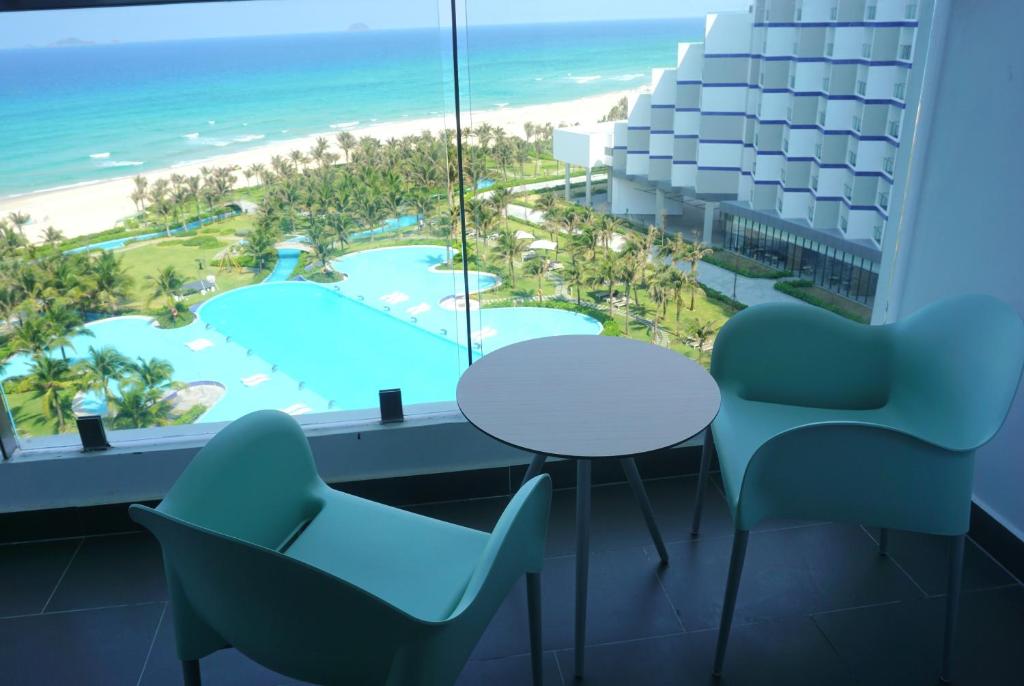 a room with a table and chairs and a view of the beach at JOY Oceanfront Serviced Apartment - Cam Ranh in Miếu Ông