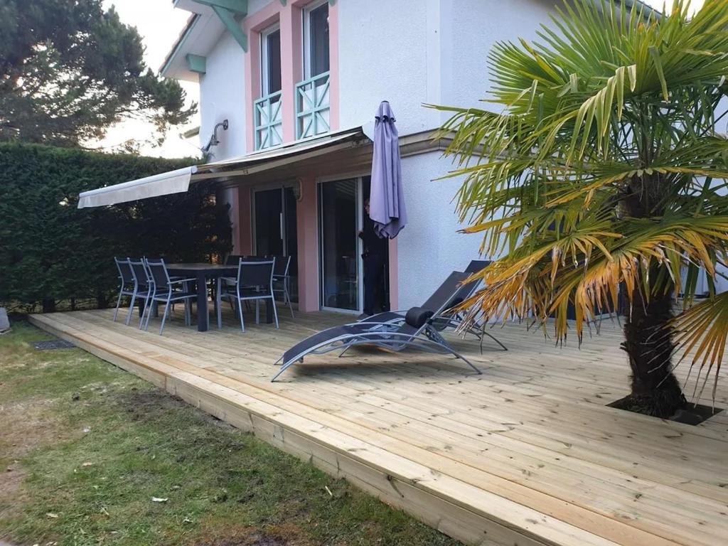 drewniany taras ze stołem i parasolem w obiekcie Biscarrosse Lac Duplex avec jardin 6 personnes w mieście Biscarrosse