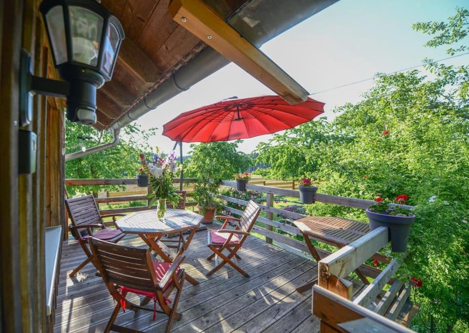 eine Terrasse mit einem Tisch, Stühlen und einem Sonnenschirm in der Unterkunft Ruhe am Waldrand in Eichendorf