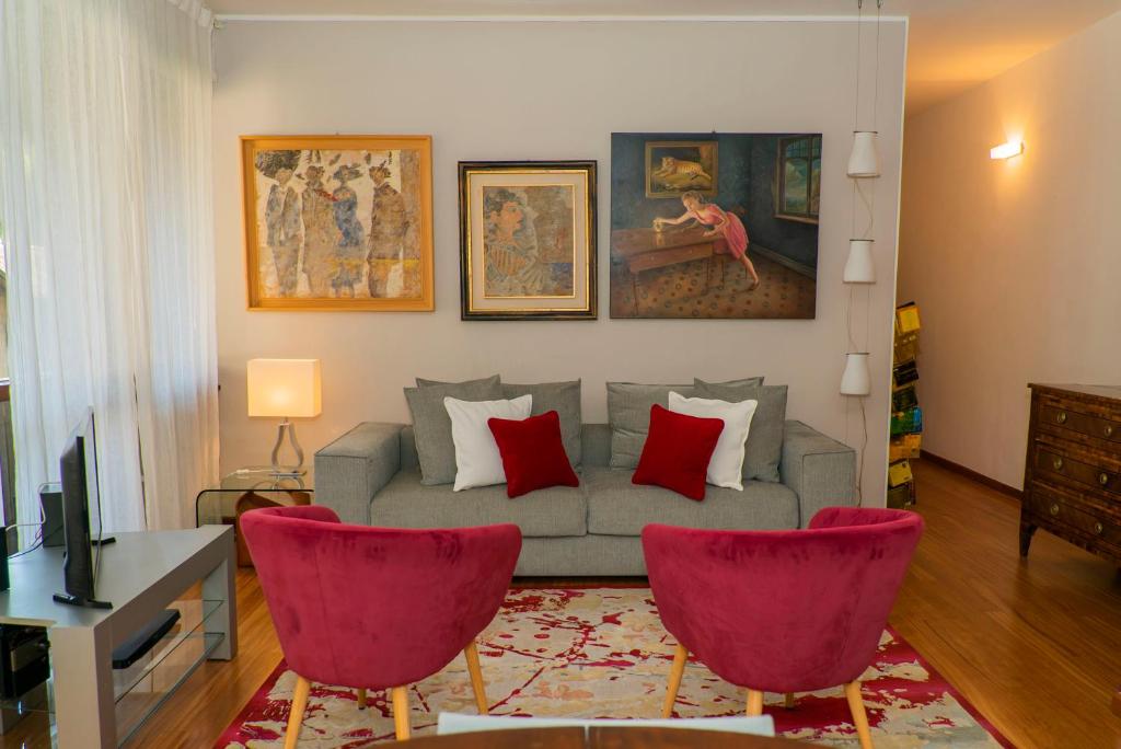 sala de estar con sofá y 2 sillas rojas en Trilocale Como Centro, Esclusivo 100 MQ con 3 Balconi, en Como