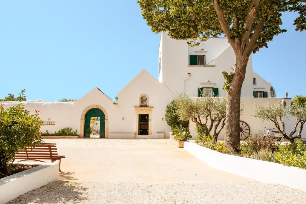 a white building with a tree and a bench at Masseria San Michele in Martina Franca
