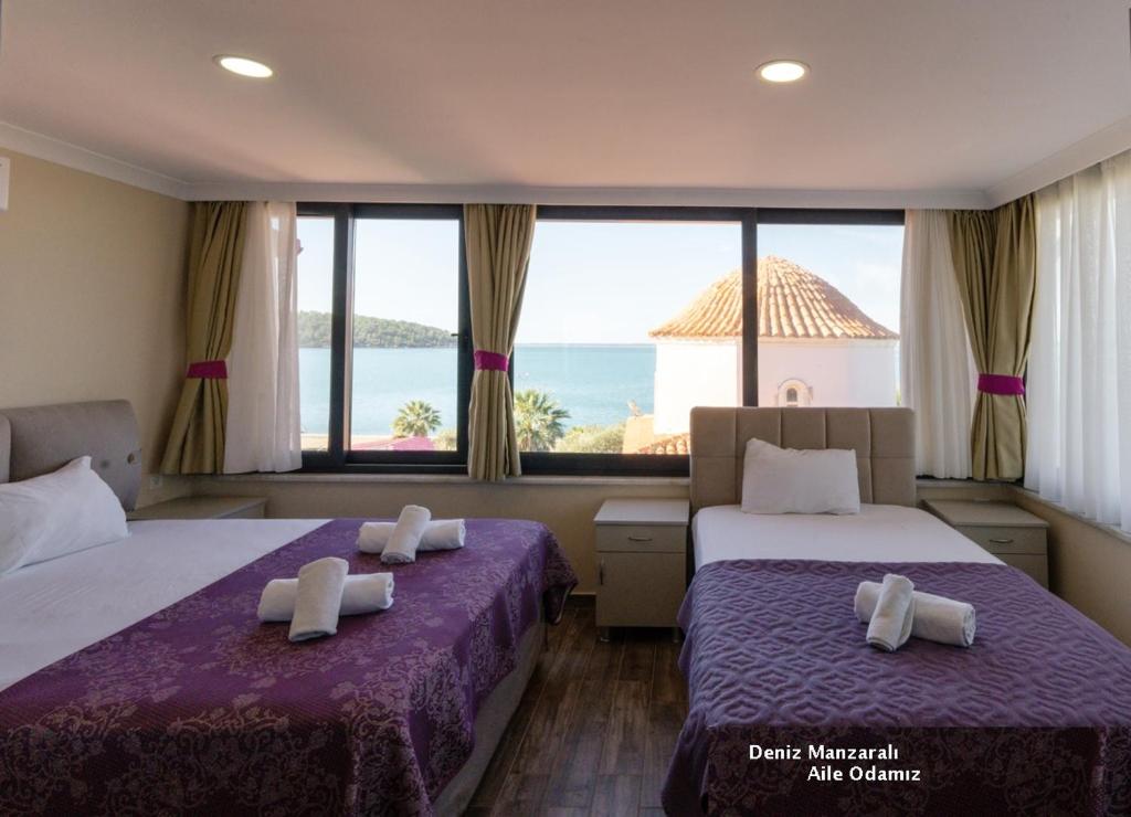two beds in a room with a view of the ocean at AKBÜK TAŞ OTEL in Akbük