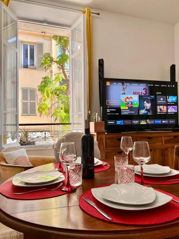 - une table avec des serviettes rouges, des verres à vin et une télévision dans l'établissement Centre heart of CAnnes, à Cannes