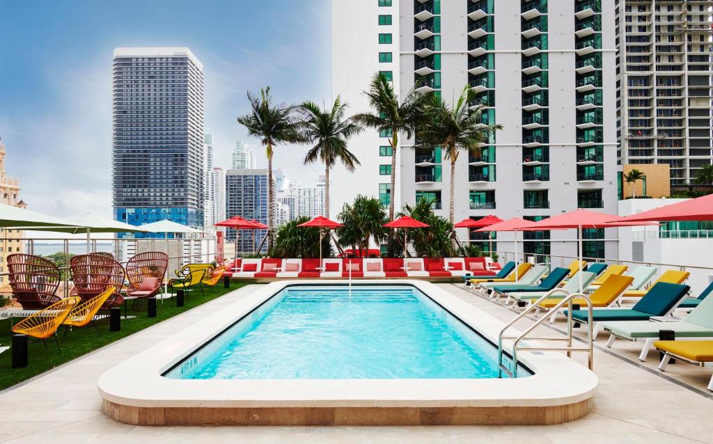 uma piscina no telhado de um edifício com cadeiras e guarda-sóis em citizenM Miami Worldcenter em Miami