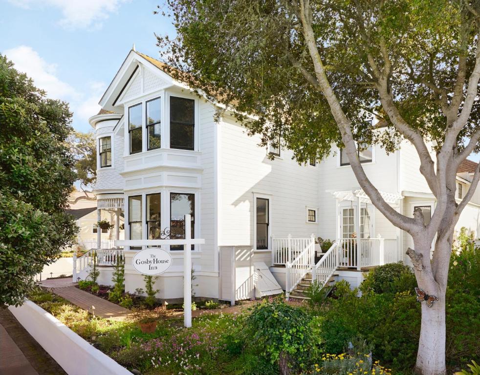 Una casa blanca con un árbol delante. en Gosby House Inn, A Four Sisters Inn en Pacific Grove