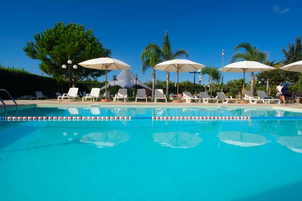 a large swimming pool with chairs and umbrellas at Lilybeo Village in Marsala