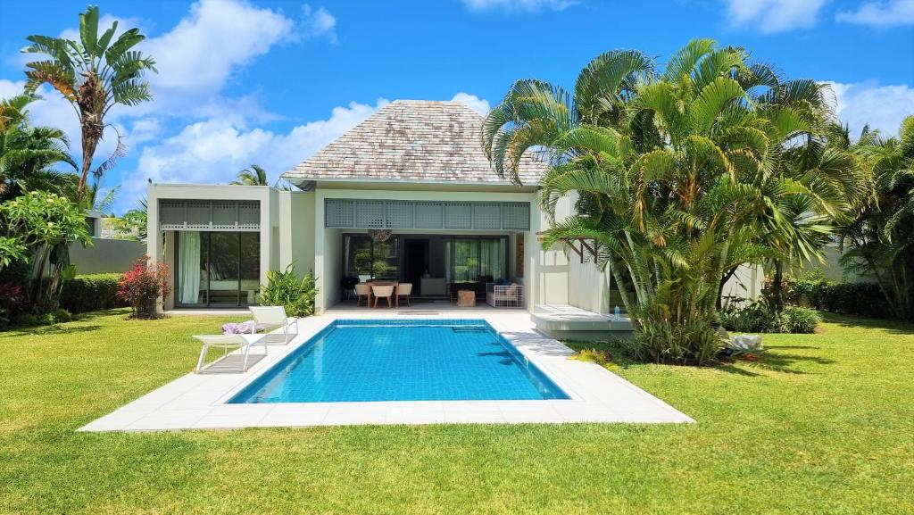 a villa with a swimming pool in front of a house at Superior 4-Bedroom Villa at Anahita Golf & Spa Resort's in Beau Champ