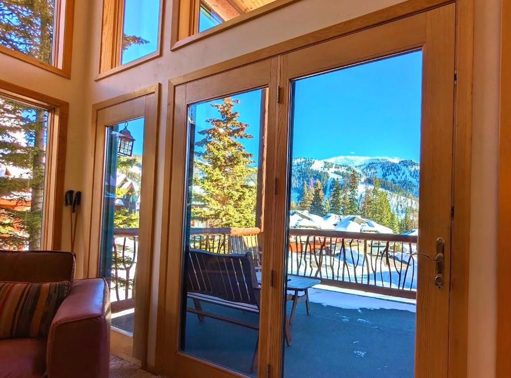 a room with a door open to a balcony with a view at Moose Tree Lodge in Whitefish