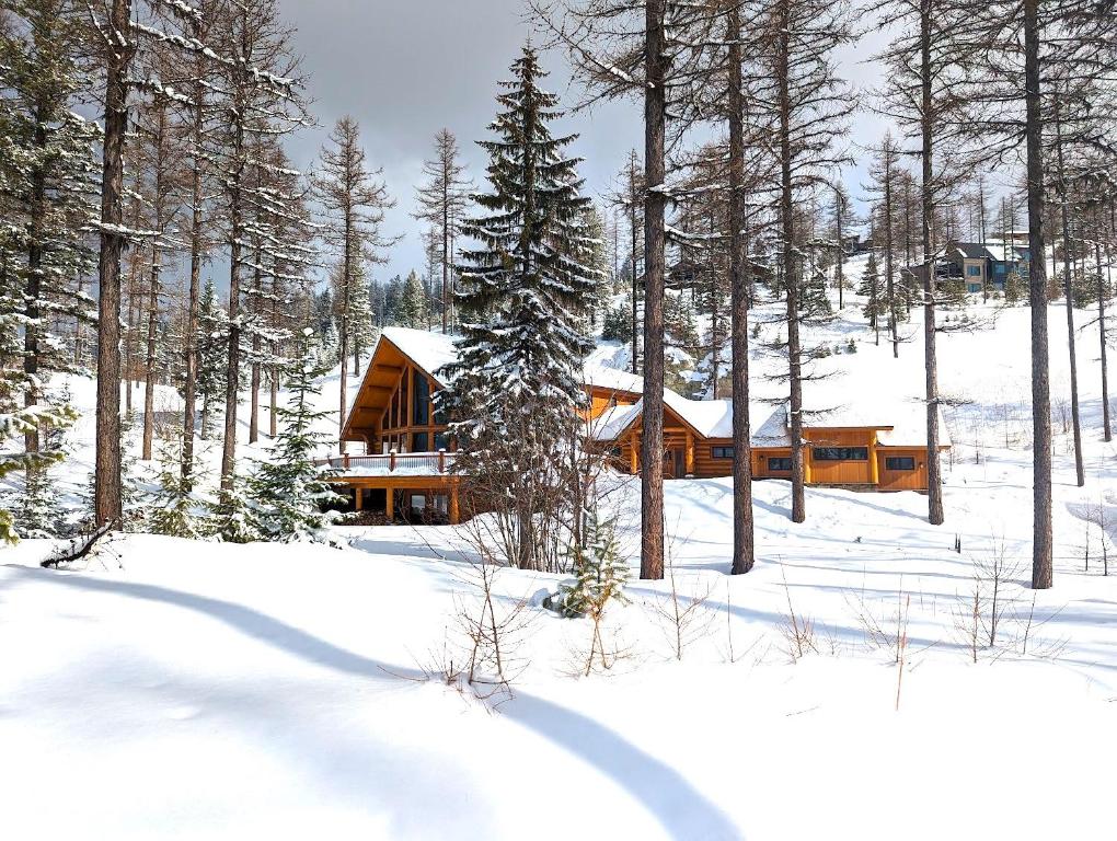 una baita di tronchi nella neve con alberi di Eagles Nest at Elk Highlands a Whitefish