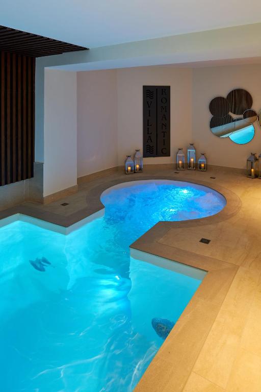 a large blue pool in a room with chairs at Hotel Villa Romantic &amp; Spa in Paris