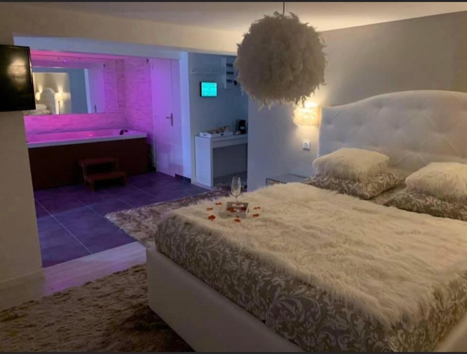 1 dormitorio con 1 cama grande con iluminación rosa en Cocon d’amour, 