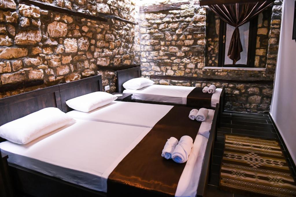 Dos camas en una habitación con zapatillas. en Bujtina Bega, en Berat