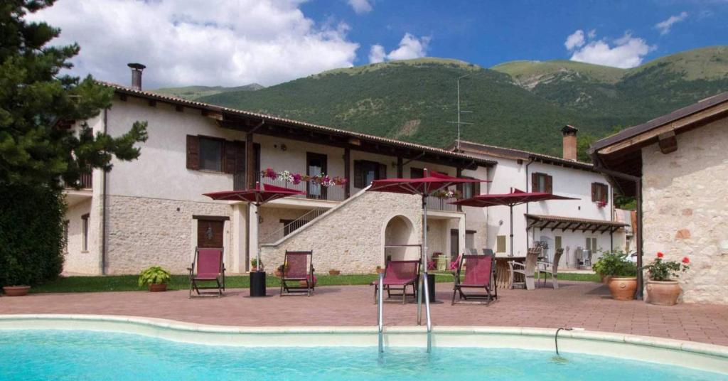 un complexe avec une piscine, des chaises et un bâtiment dans l'établissement Agriturismo Le Case di Quarantotti, à Norcia