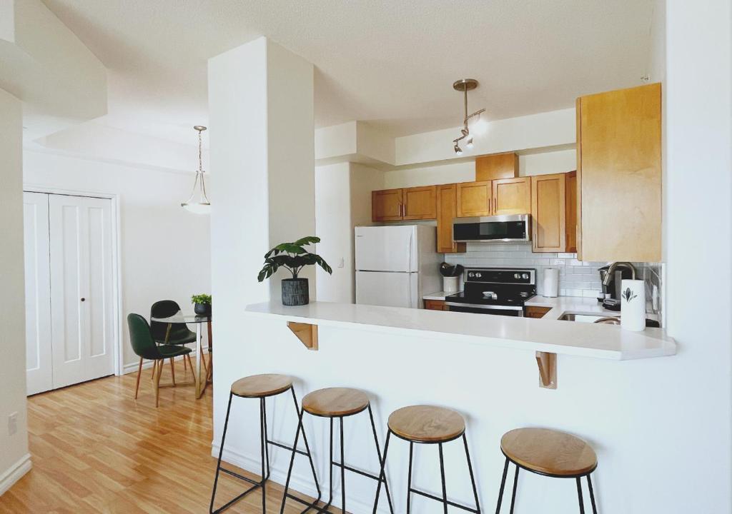 a kitchen with wooden cabinets and bar stools at DOWNTOWN WATERFRONT KELOWNA OASIS Newly Renovated 2Bed 2Bath in Kelowna