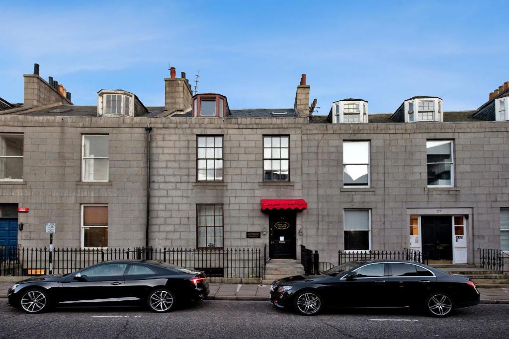 two black cars parked in front of a building at Inviting 9-Bed House in Aberdeen in Aberdeen